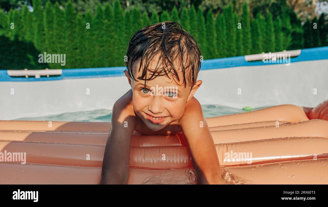Un ragazzo carino con una nuotata che si gode l'estate nel cortile sul retro Foto Stock