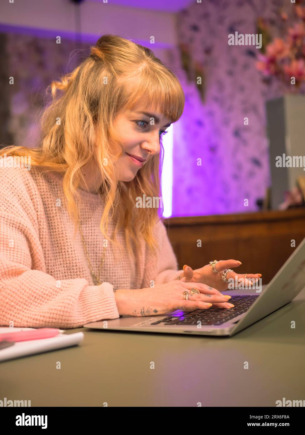 Felice freelance che indossa un maglione con il laptop a casa Foto Stock