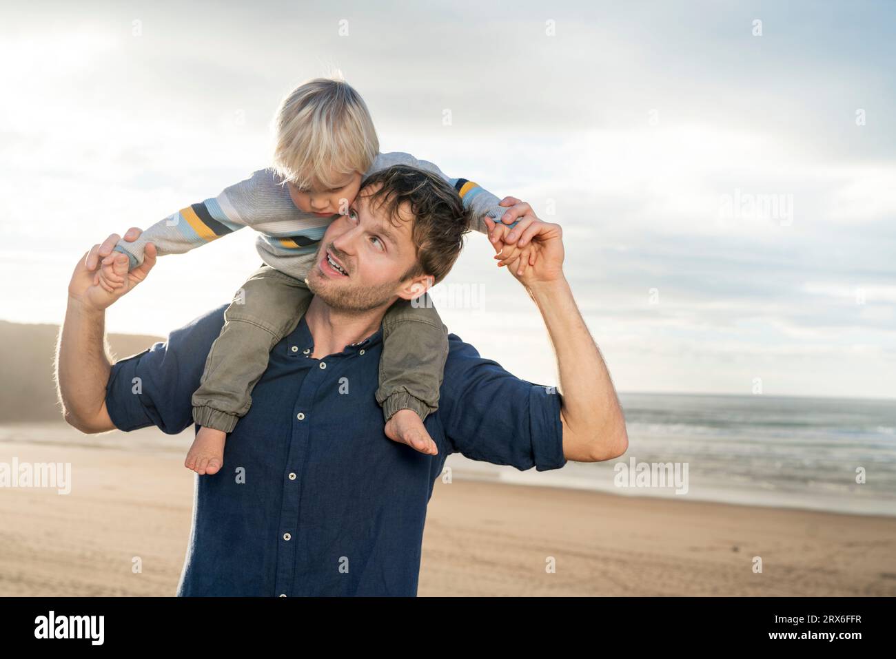 Padre felice che porta un bambino sulle spalle in spiaggia Foto Stock