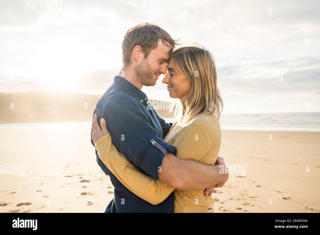 Sorridente uomo e donna che si abbracciano in spiaggia Foto Stock