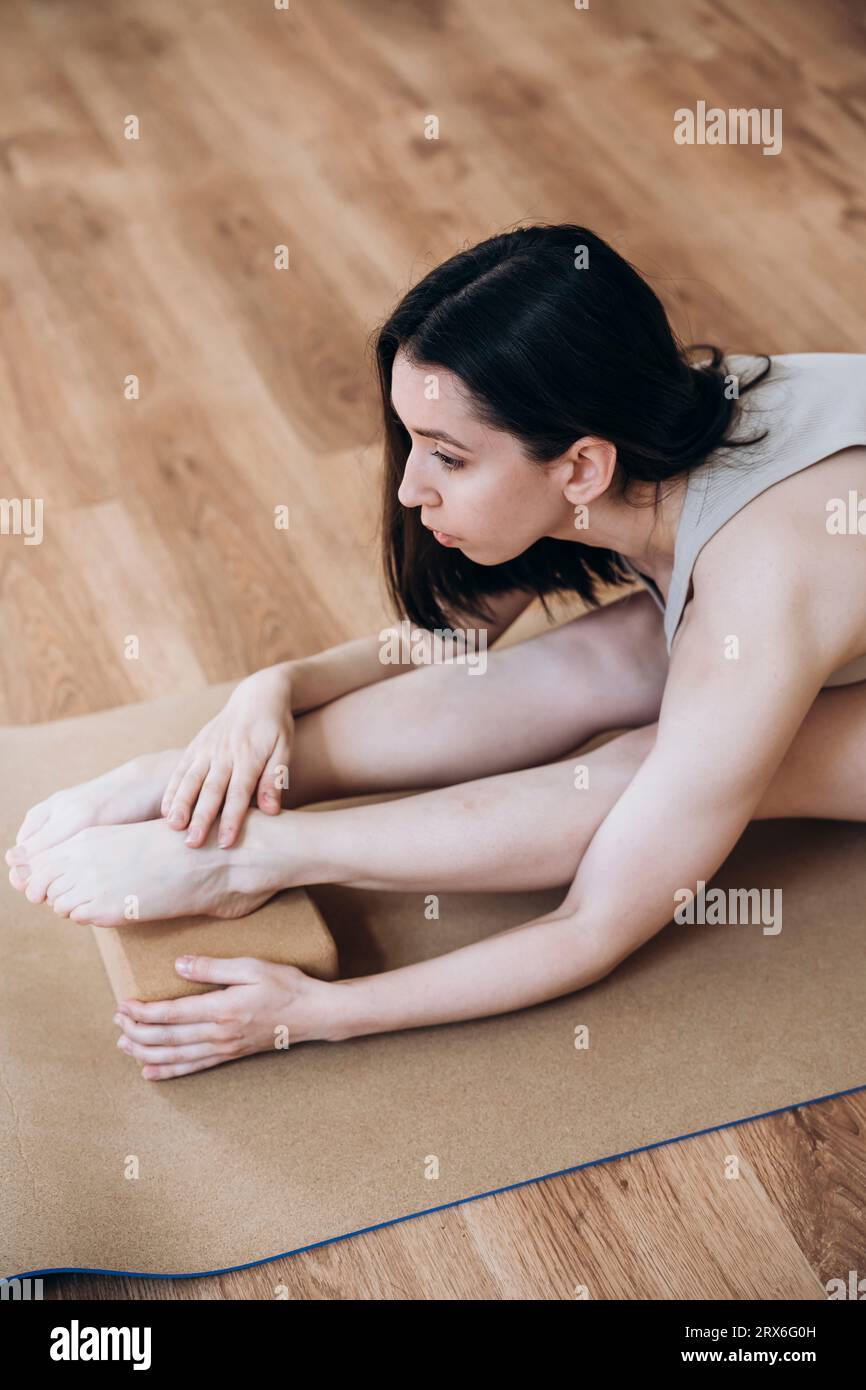 Donna che si piega in avanti e fa yoga in studio Foto Stock