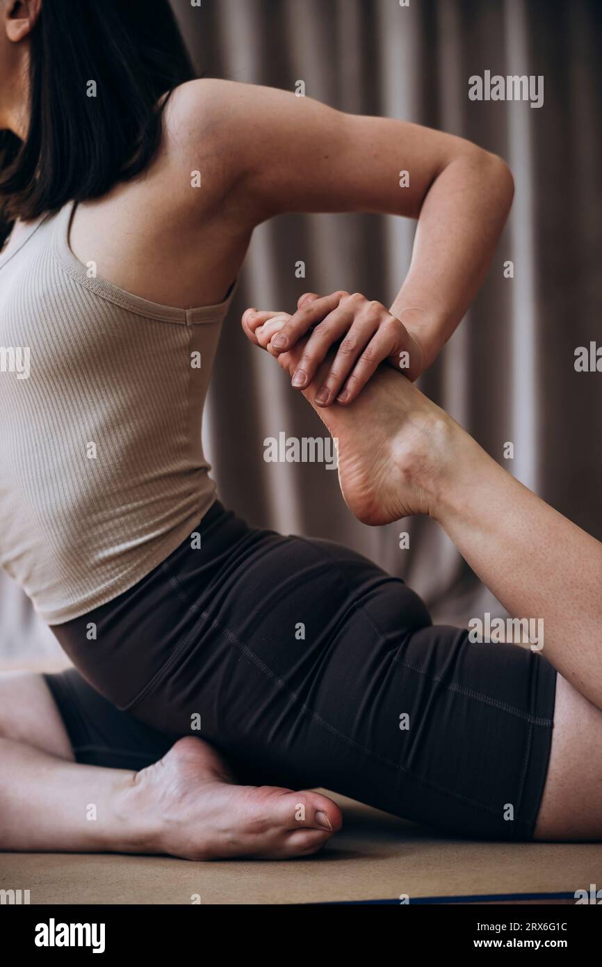 Giovane donna che allunga le gambe nello studio di yoga Foto Stock