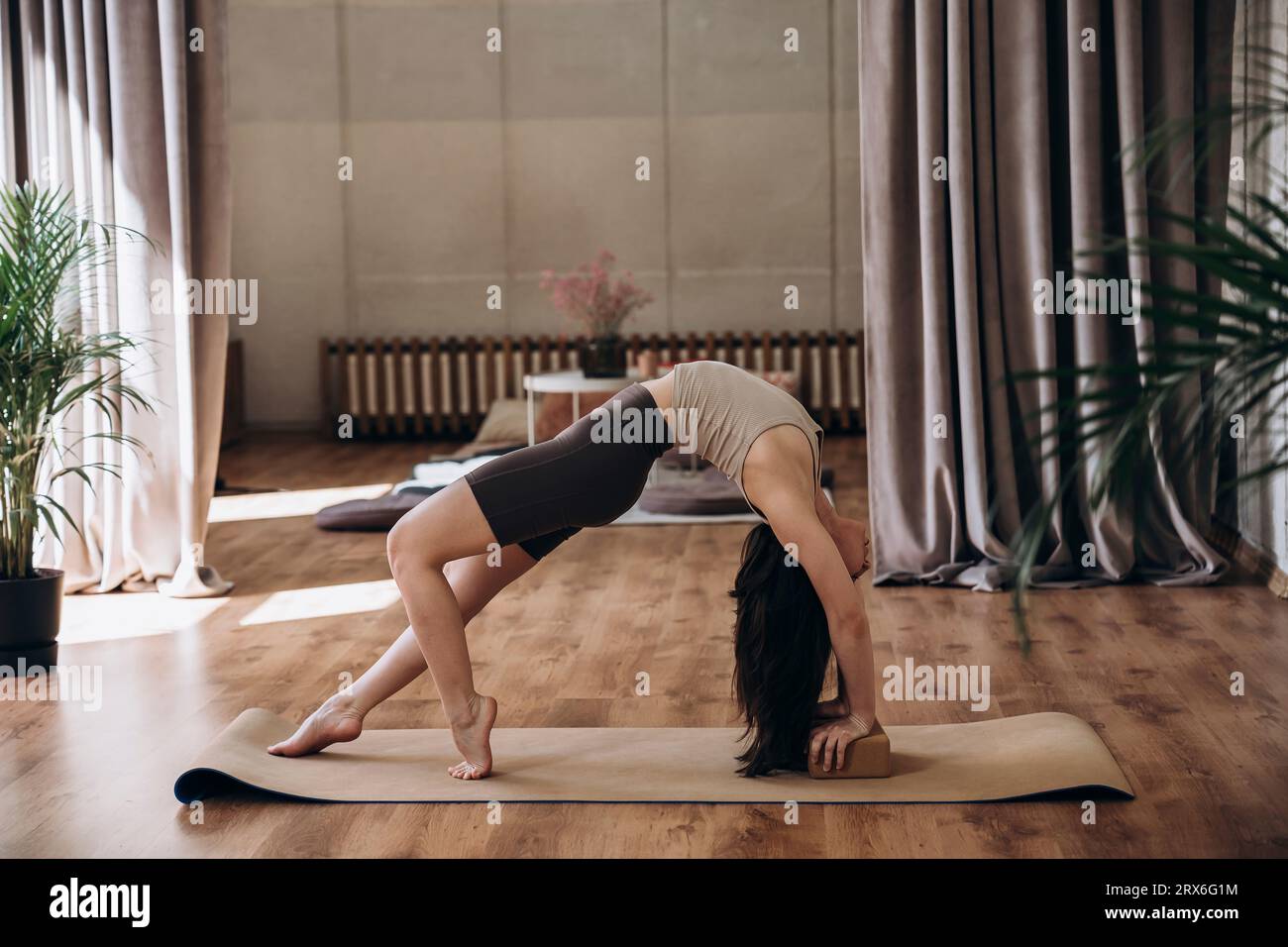 Giovane donna che si piega all'indietro e fa yoga in palestra Foto Stock