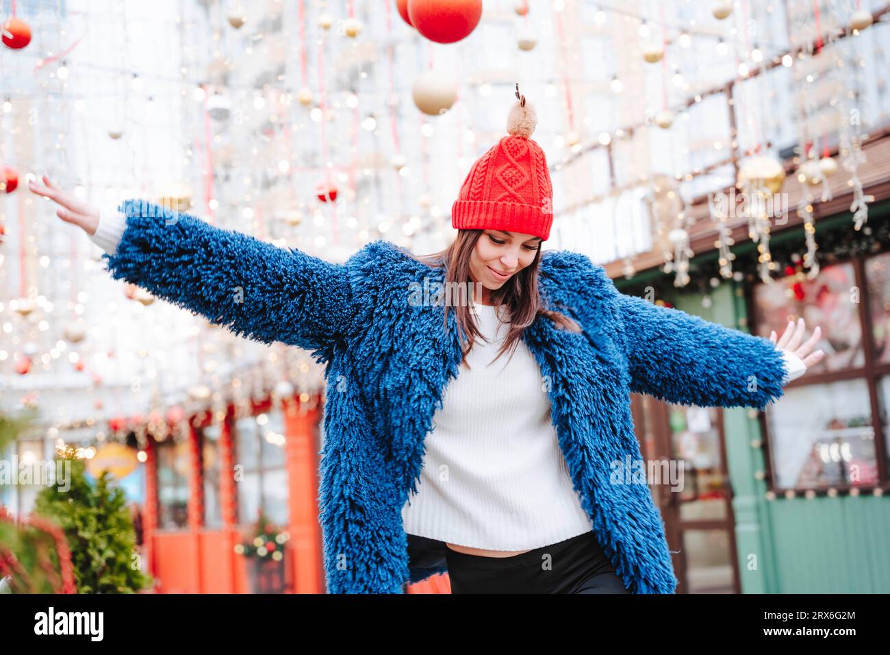 Donna sorridente che indossa un cappotto blu che balla in città Foto Stock