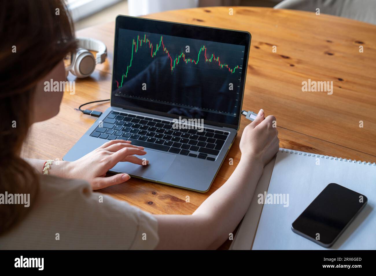 Donna d'affari che analizza i dati di trading degli investimenti su un laptop a casa Foto Stock