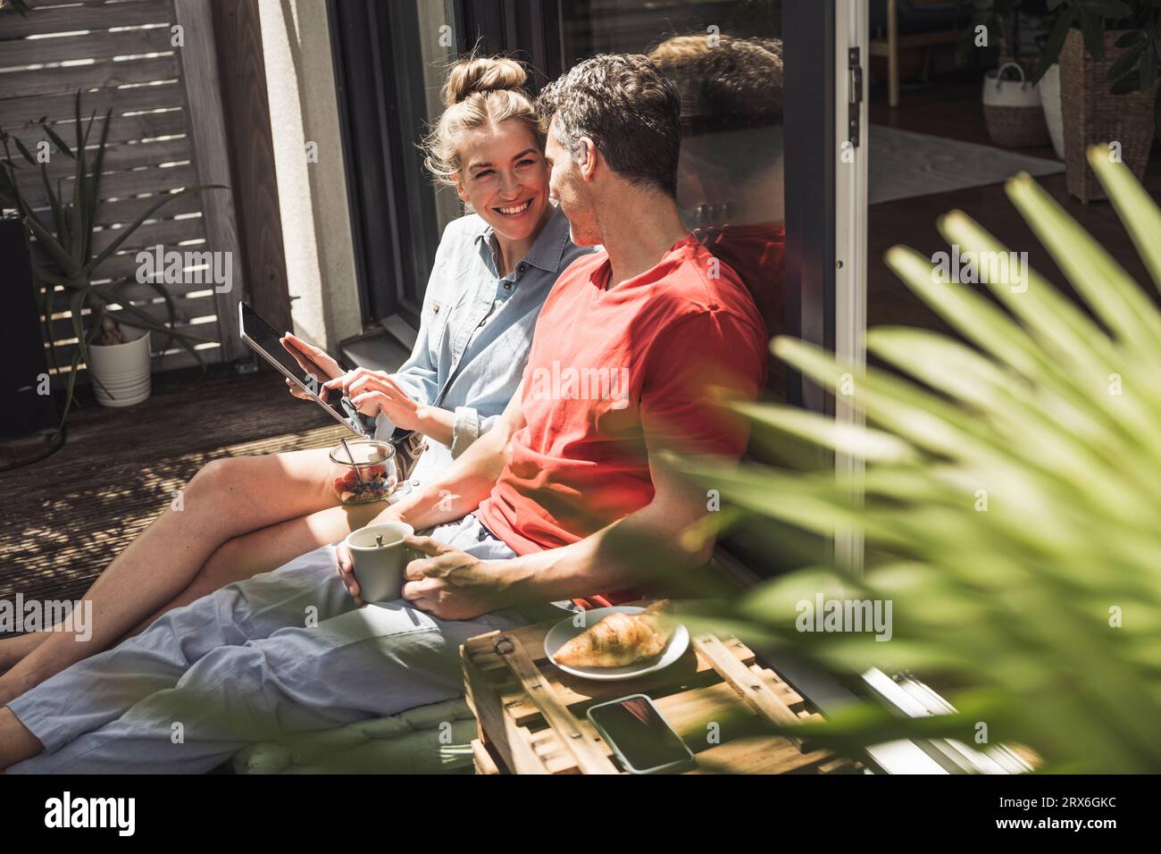 Coppia che si rilassa sul balcone con un tablet digitale Foto Stock