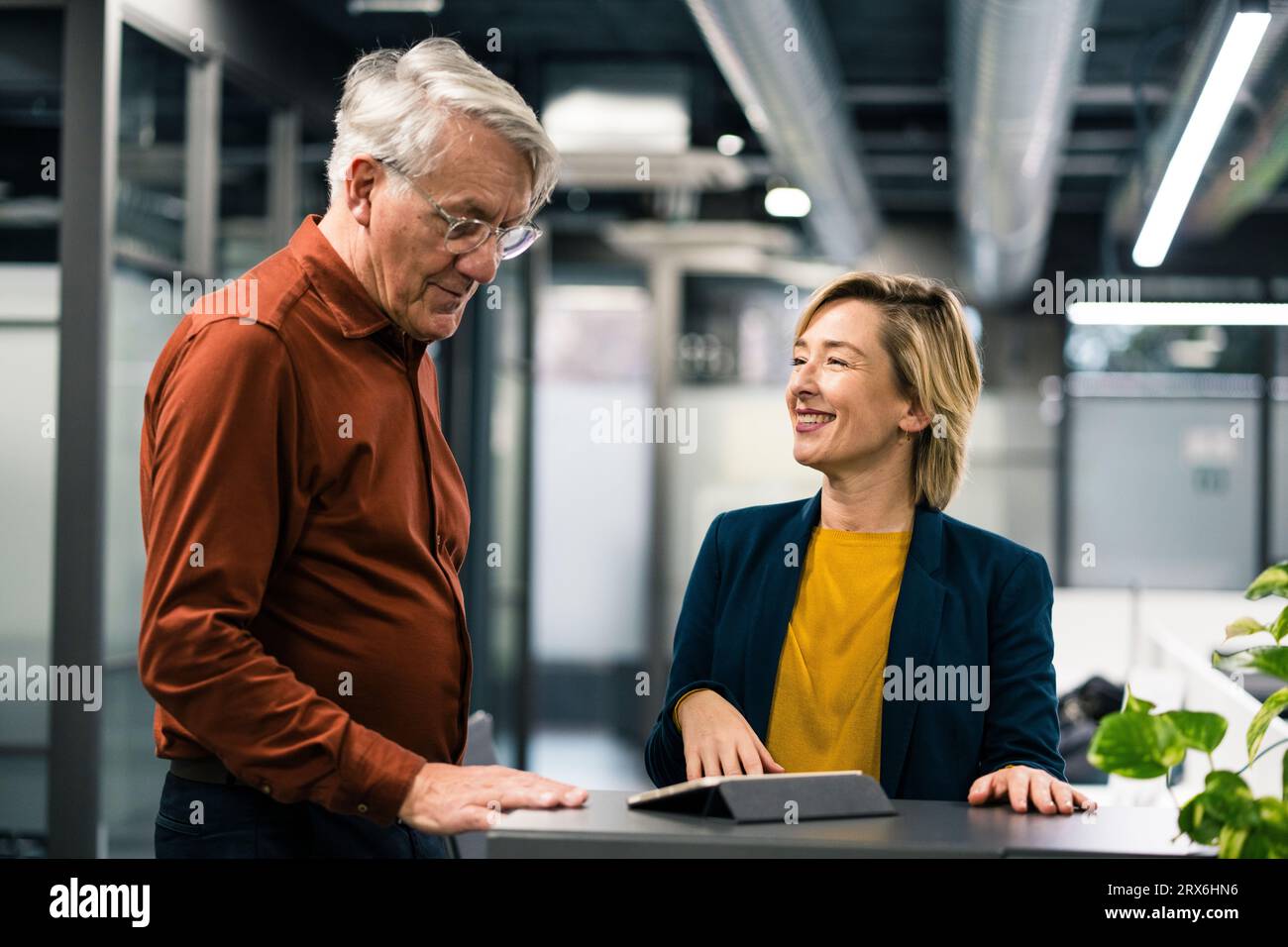 Un uomo d'affari sorridente e una donna d'affari che pianificano una strategia in ufficio Foto Stock