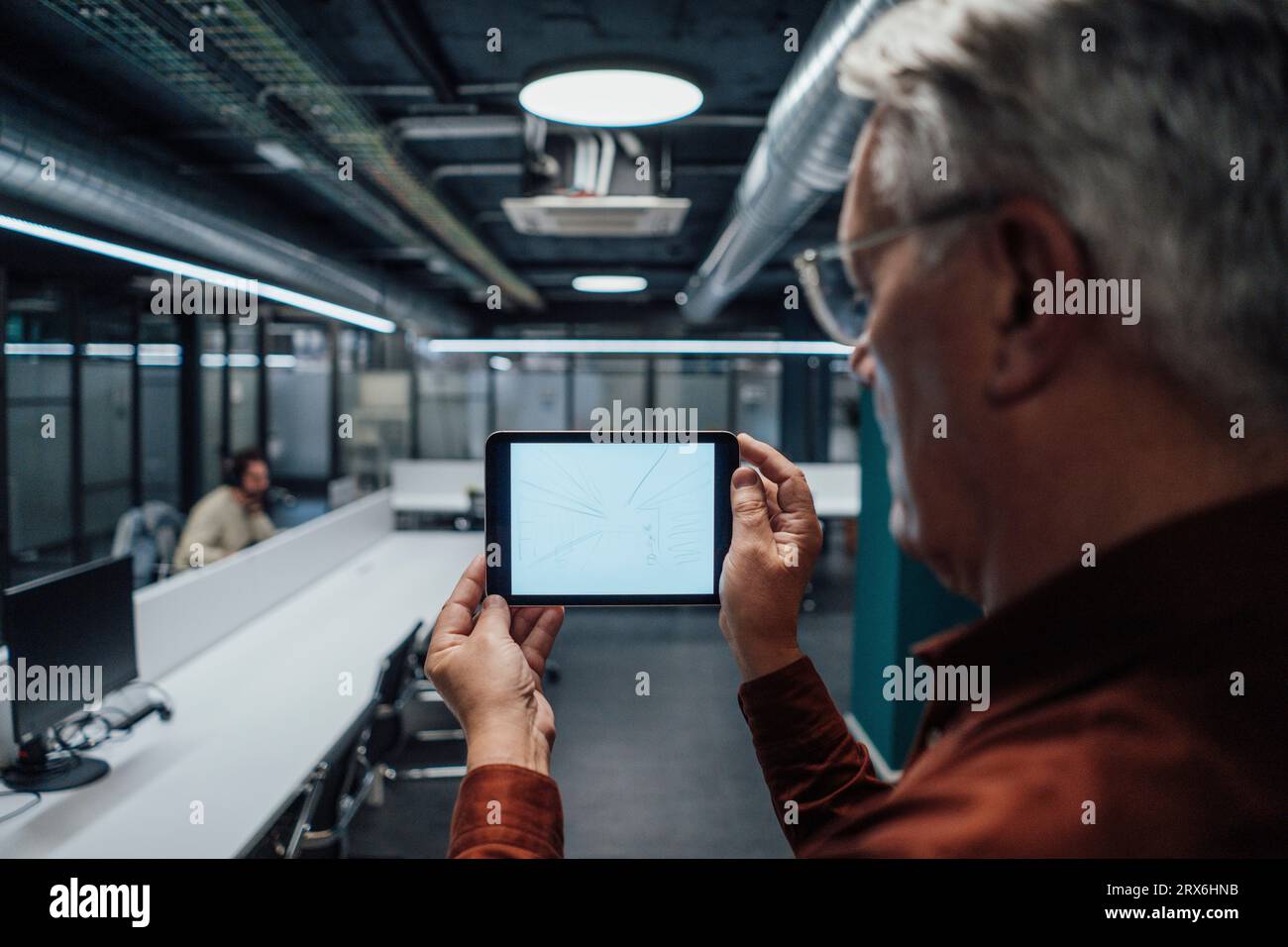 Uomo d'affari anziano che esamina il progetto su un tablet PC in ufficio Foto Stock