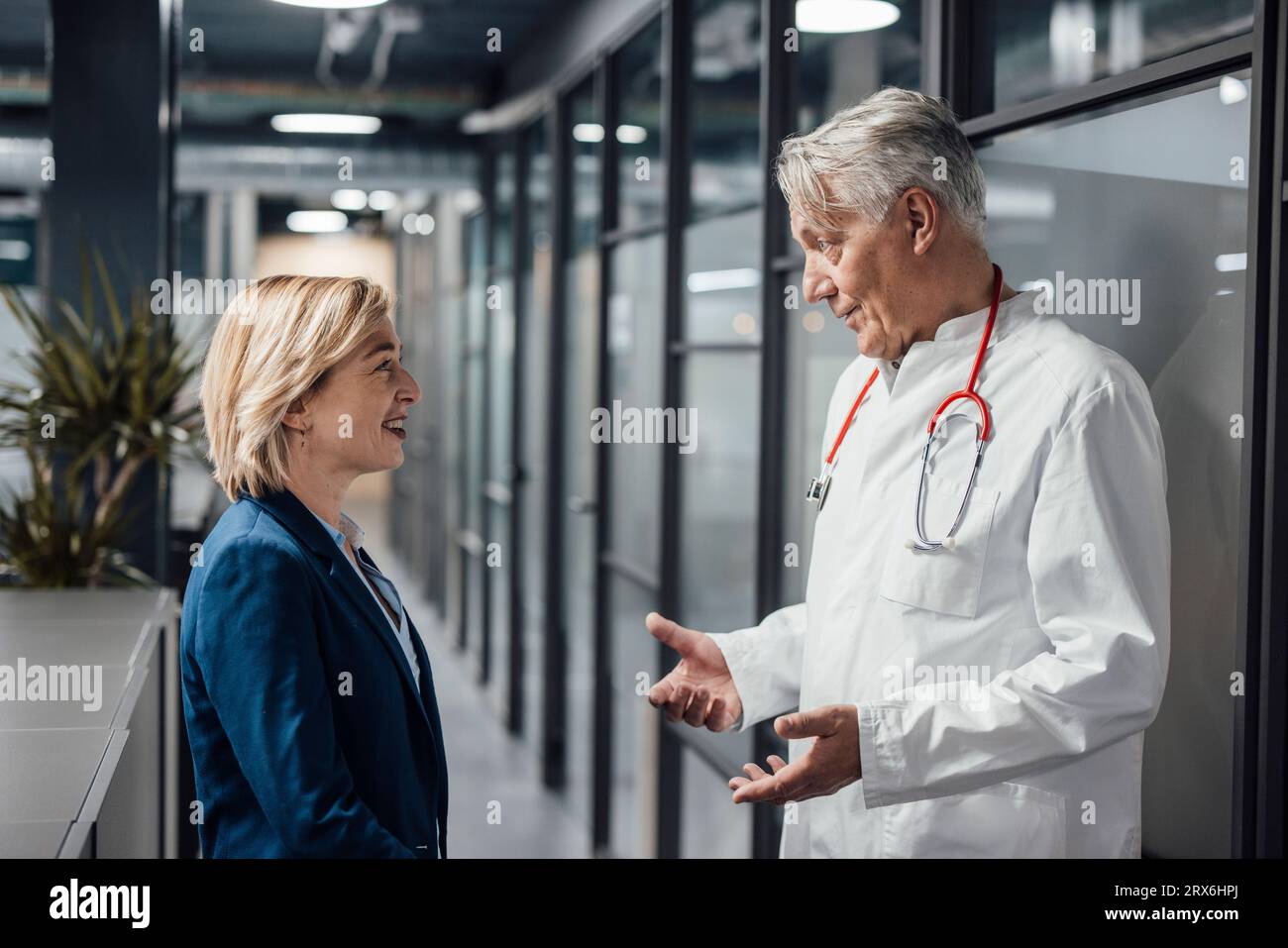 Paziente sorridente che ascolta il medico che parla in ospedale Foto Stock