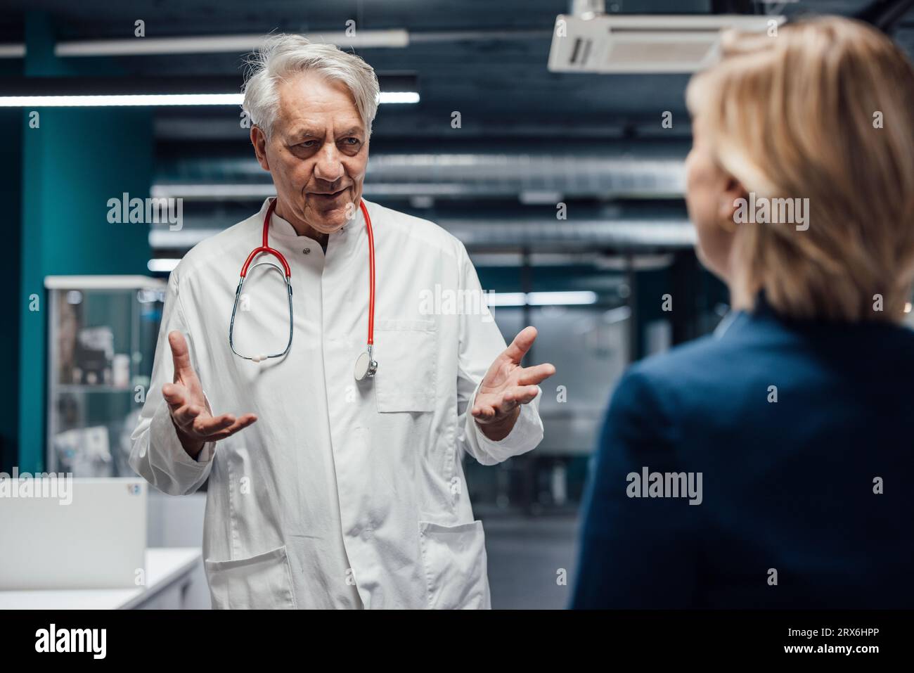 Medico anziano gestante e spiegazione al paziente in clinica Foto Stock