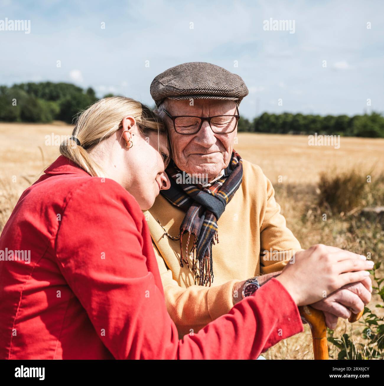 Donna appoggiata alla spalla di un uomo anziano nelle giornate di sole Foto Stock