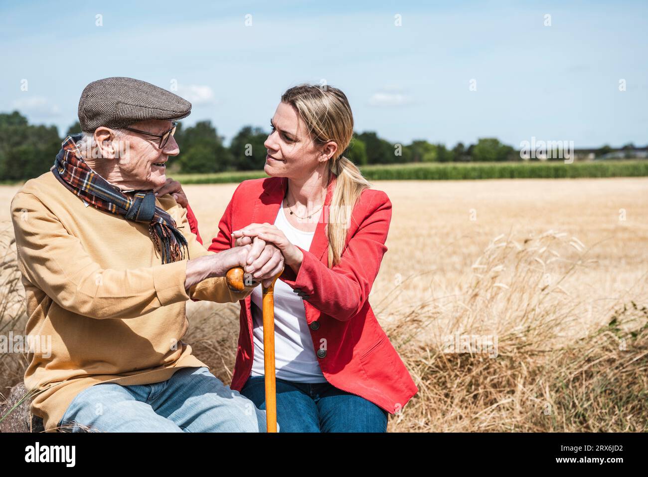 Donna che parla con un uomo anziano sul campo nelle giornate di sole Foto Stock