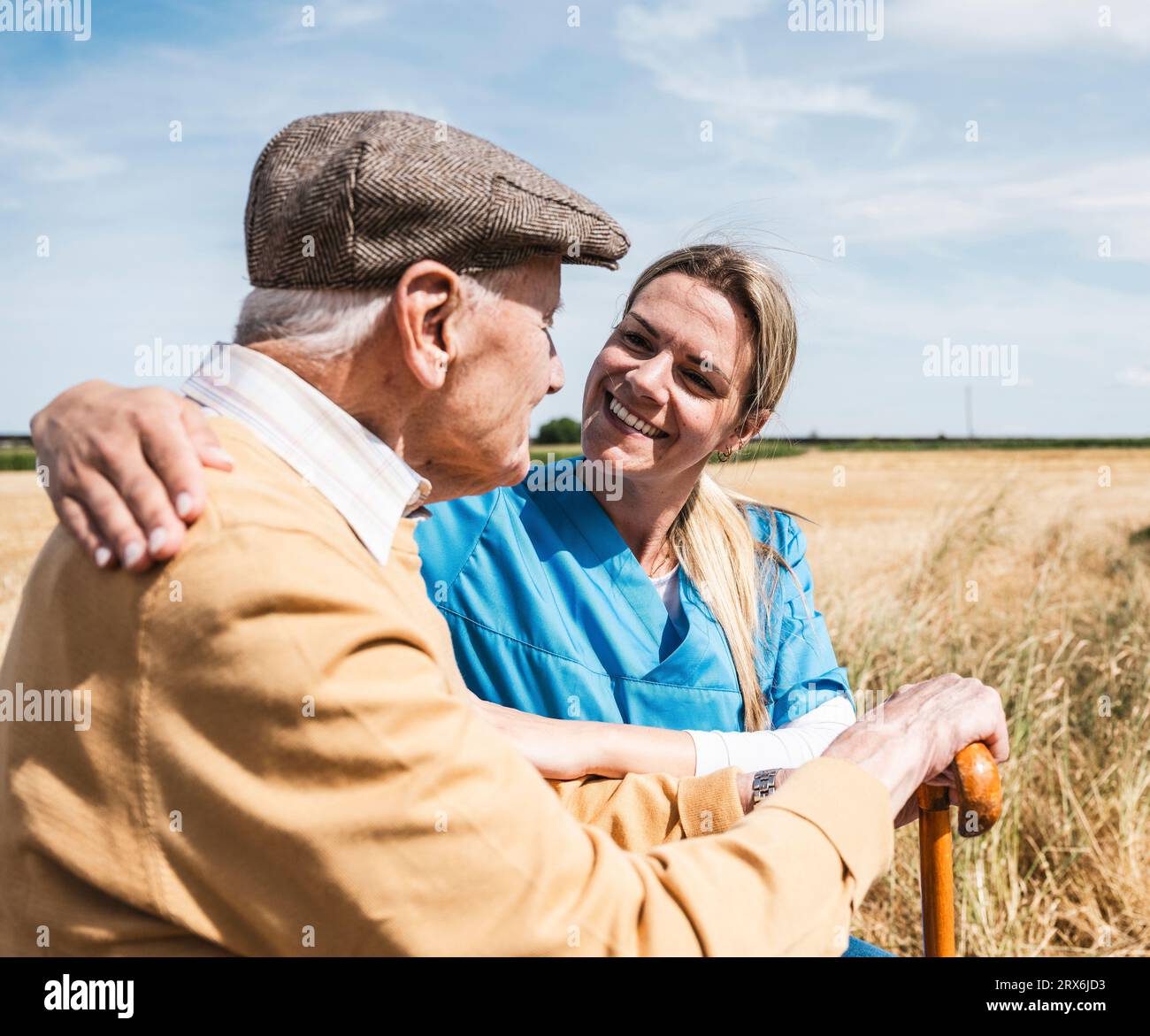 Un'infermiera felice che si prende cura di un uomo anziano nelle giornate di sole Foto Stock