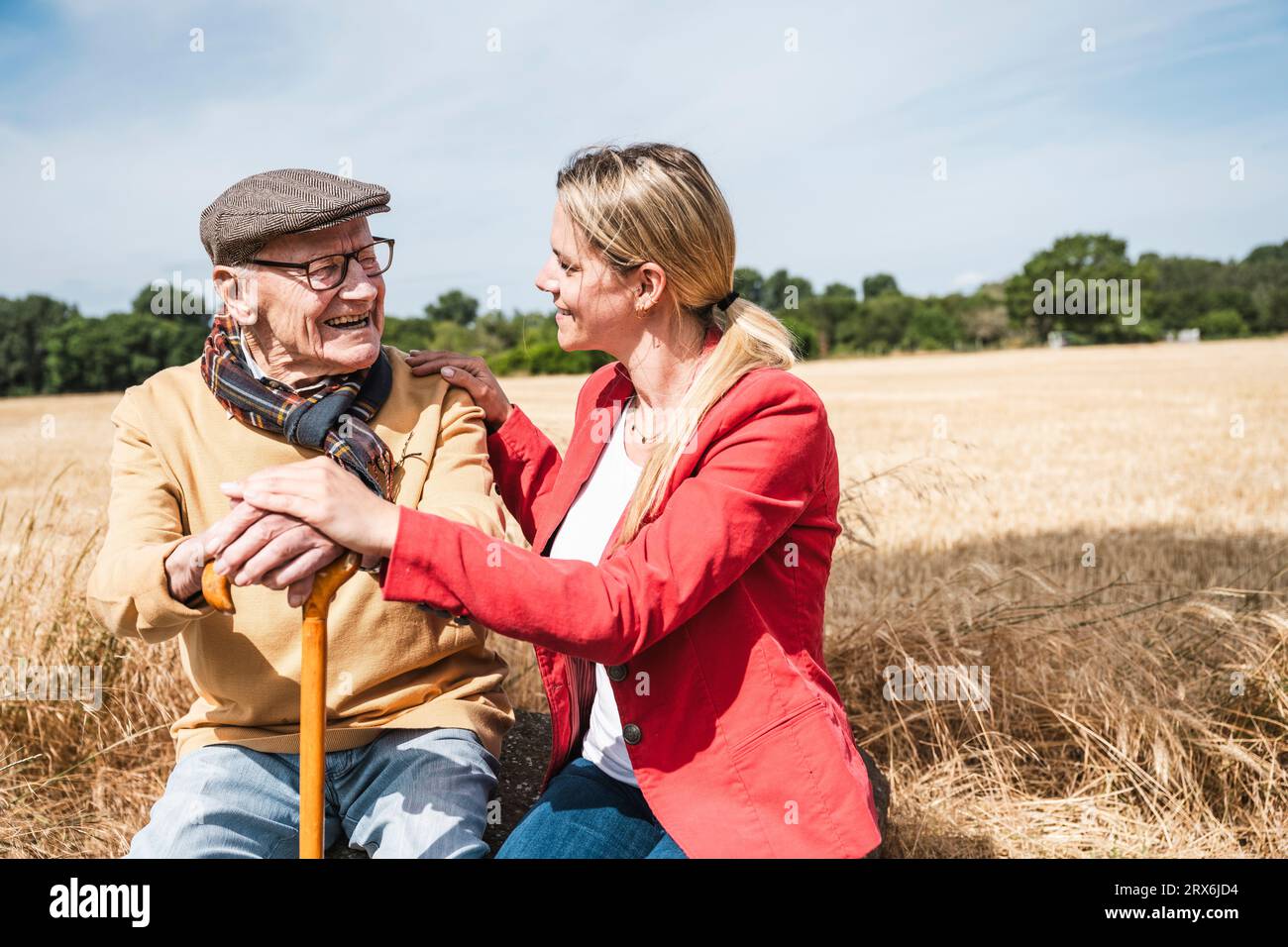 Un uomo anziano allegro che parla con una donna sul campo nelle giornate di sole Foto Stock