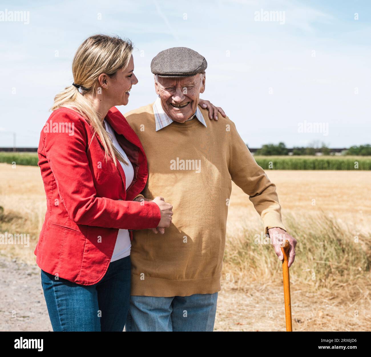 Un uomo anziano felice che cammina con una donna a campo nelle giornate di sole Foto Stock