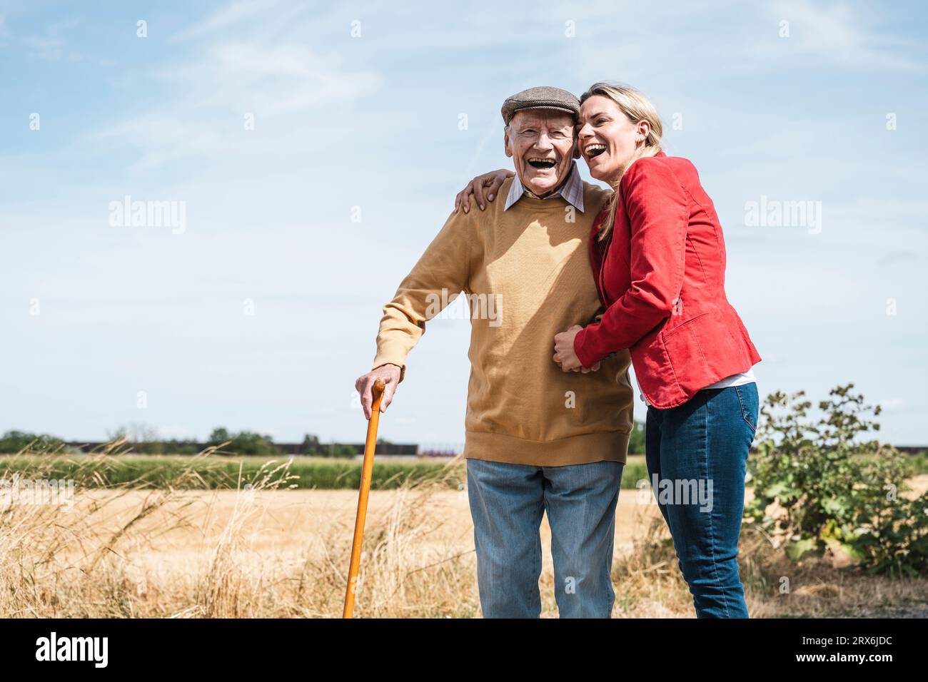 Donna allegra che abbraccia un uomo anziano in piedi accanto al campo Foto Stock