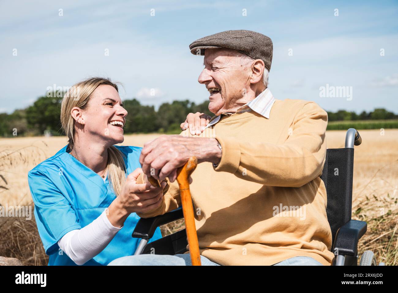 Infermiere e anziano con disabilità che ridono nelle giornate di sole Foto Stock