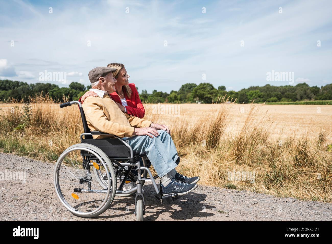Uomo anziano seduto in sedia a rotelle da una donna e guardando il campo Foto Stock