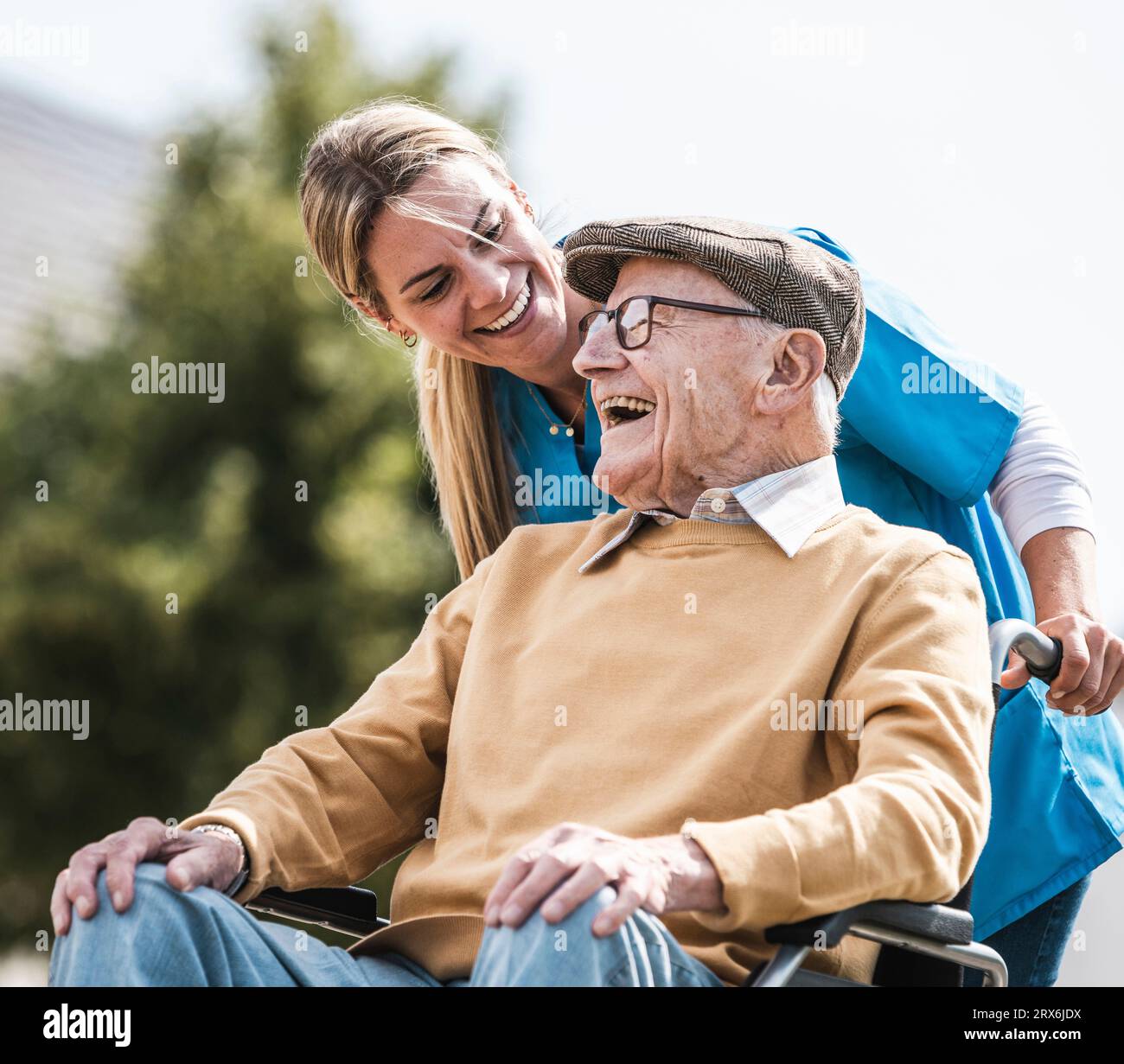 Lavoratore sanitario felice che parla con l'uomo anziano con disabilità Foto Stock