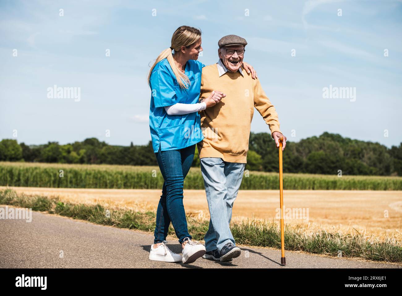 Infermiera che tiene per mano un uomo anziano e cammina per strada Foto Stock