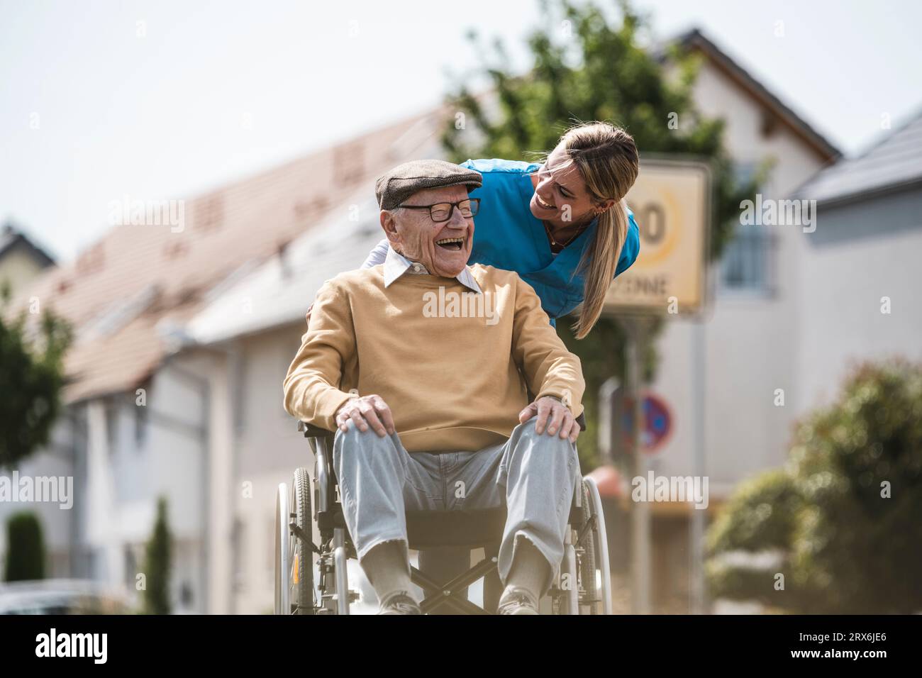 Allegra infermiera che parla con un anziano seduto in sedia a rotelle Foto Stock