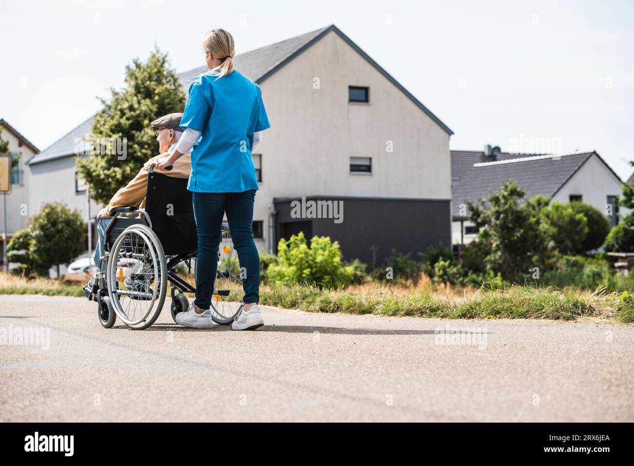 Operatore sanitario che spinge l'uomo anziano seduto in sedia a rotelle Foto Stock