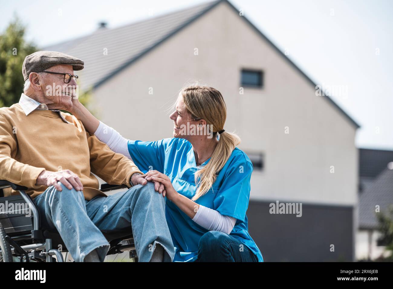Infermiera che guarda un uomo anziano seduto in sedia a rotelle Foto Stock