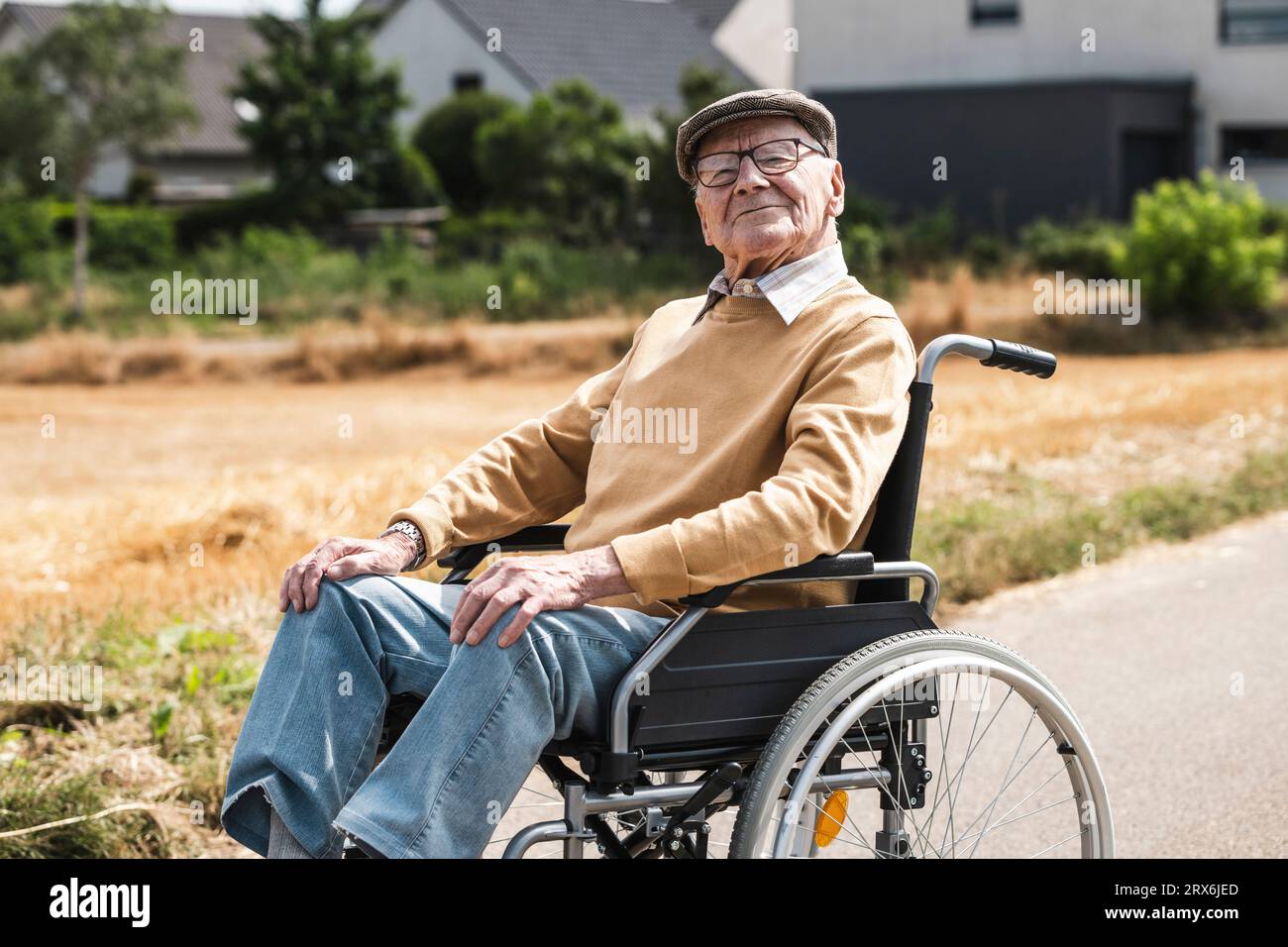 Uomo anziano con occhiali da vista seduto in sedia a rotelle Foto Stock