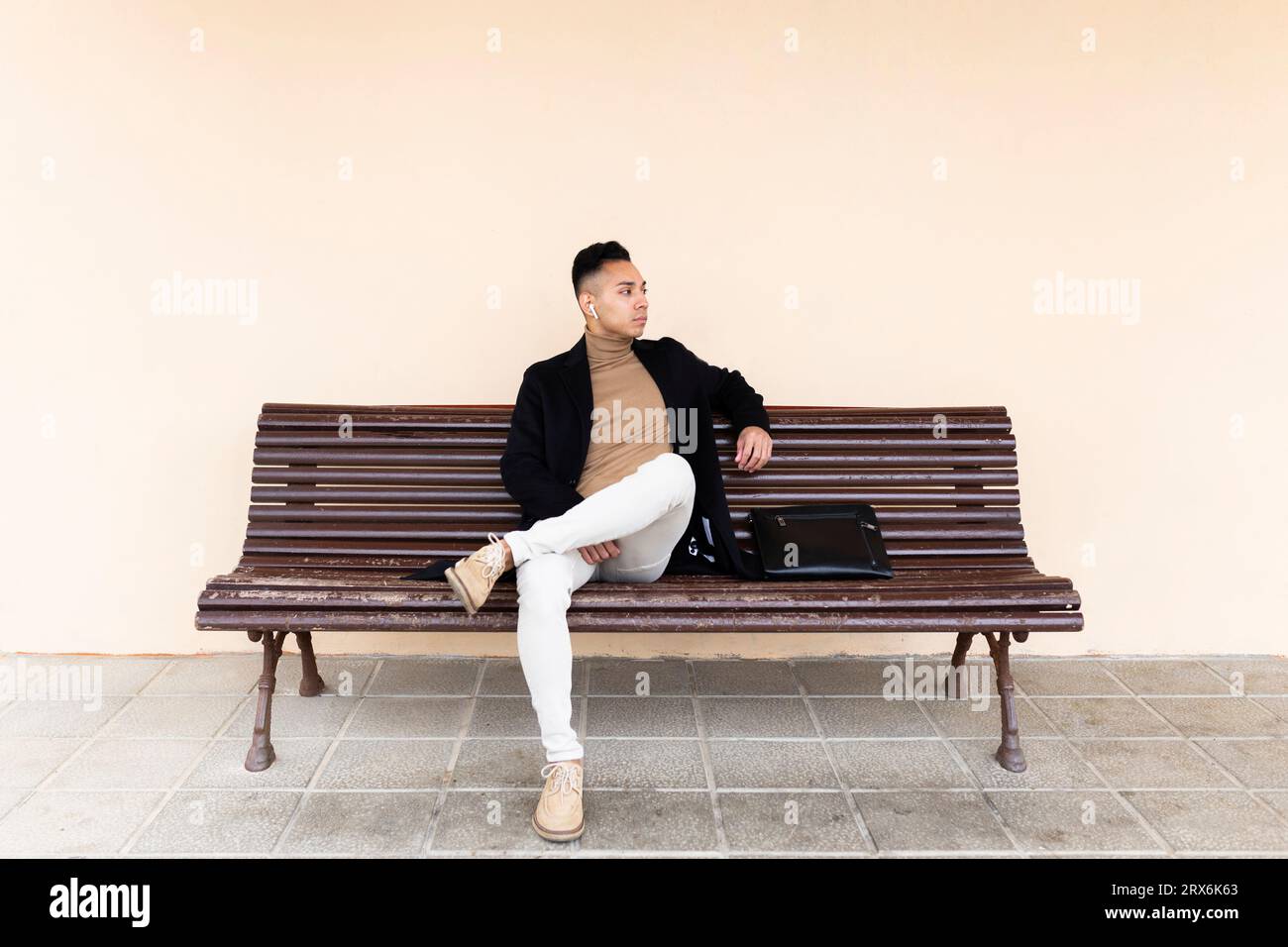Uomo contemplativo seduto sulla panchina alla stazione ferroviaria Foto Stock