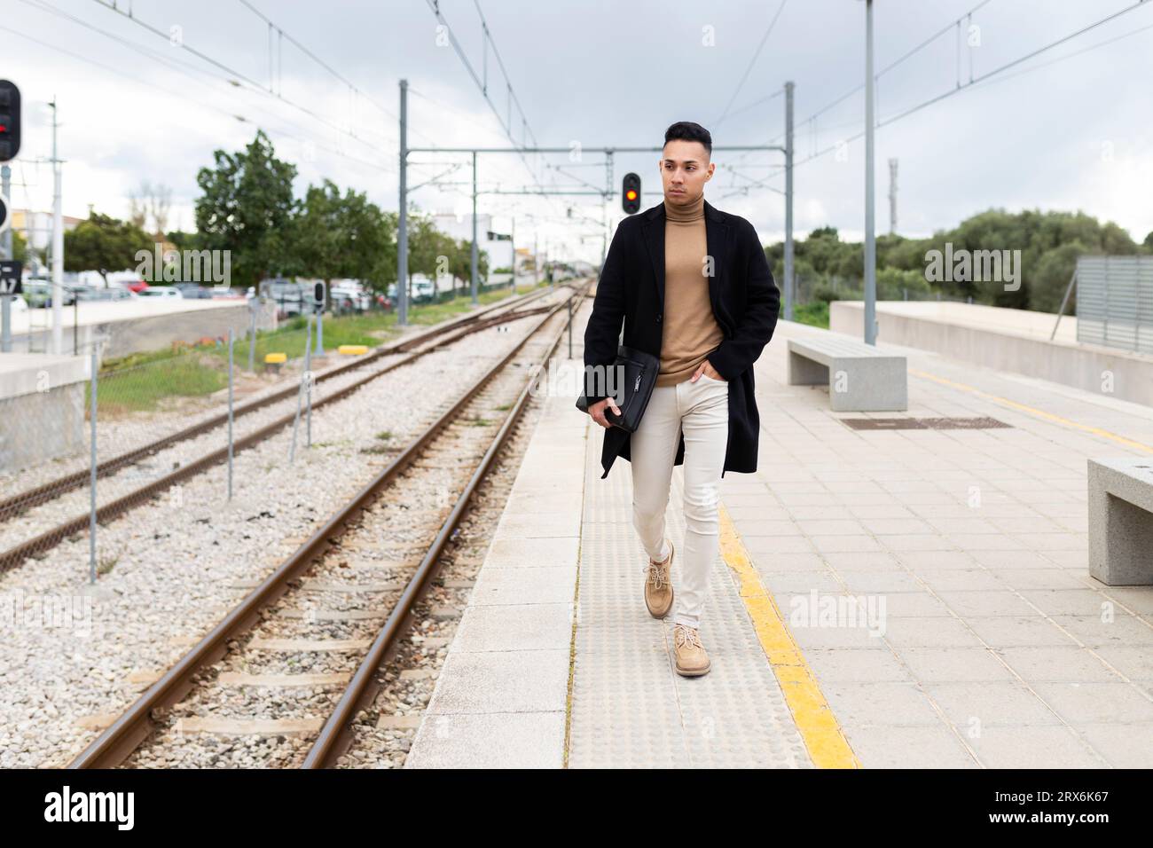 Giovane uomo che cammina sulla piattaforma della stazione ferroviaria Foto Stock