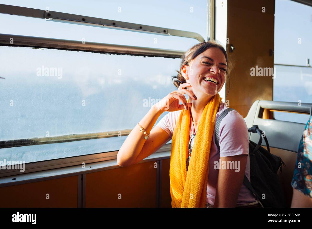 Donna felice seduta in treno vicino alla finestra Foto Stock