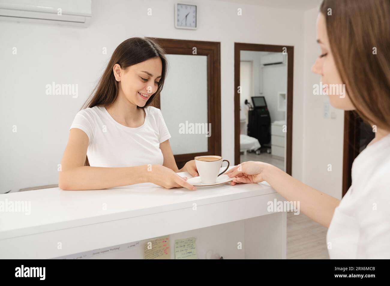La receptionist serve una tazza di caffè al cliente in clinica Foto Stock