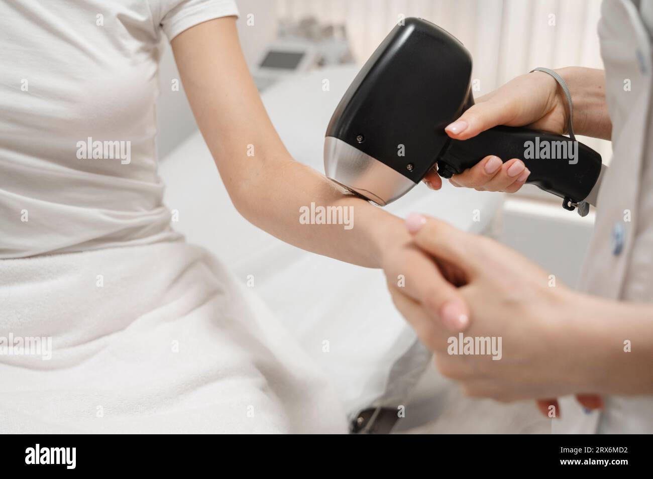 Cosmetologo che rimuove i capelli con il laser sulla mano della donna Foto Stock