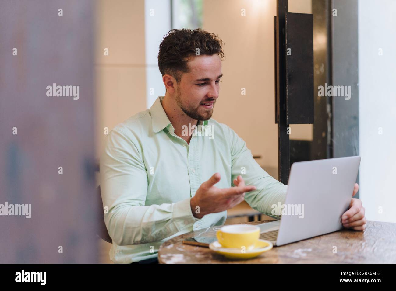 Un giovane uomo d'affari sorridente che parla in videochiamata tramite laptop Foto Stock