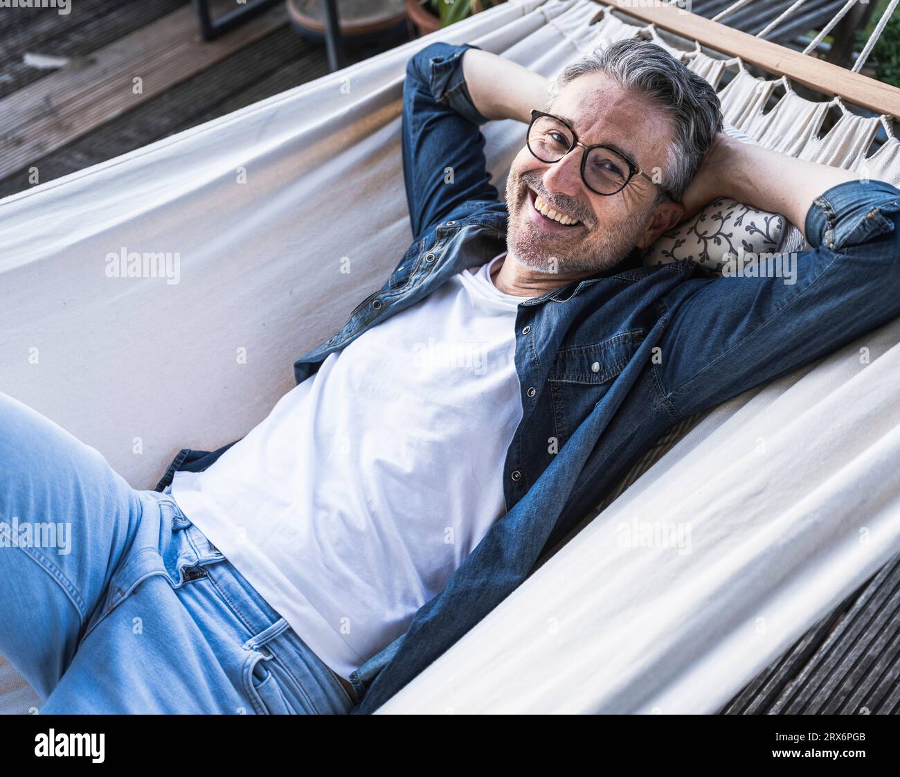 Un uomo maturo felice che si rilassa in un'amaca a casa Foto Stock