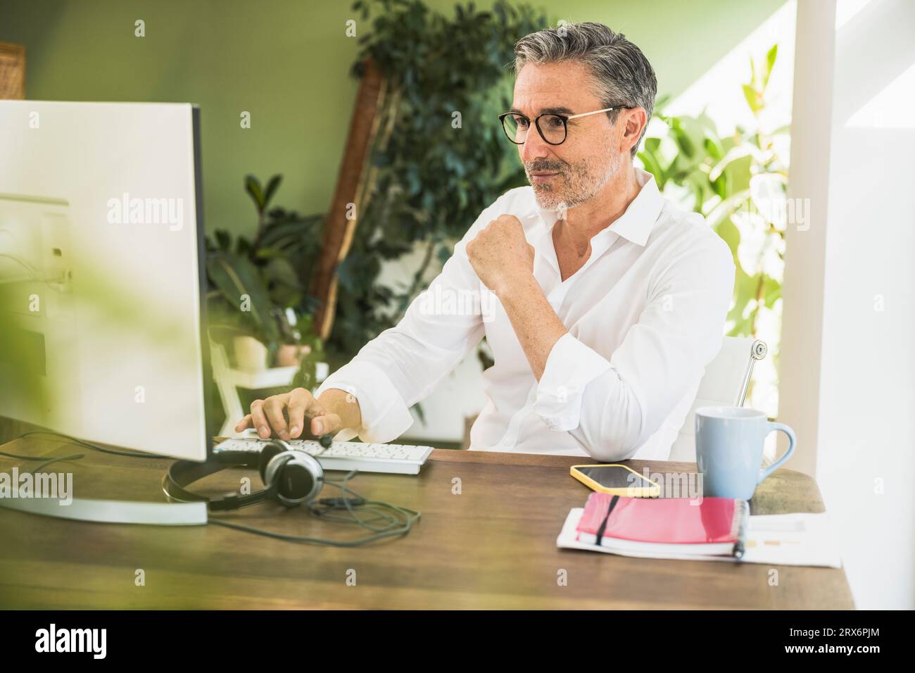 Freelance che lavora al computer alla scrivania in ufficio Foto Stock