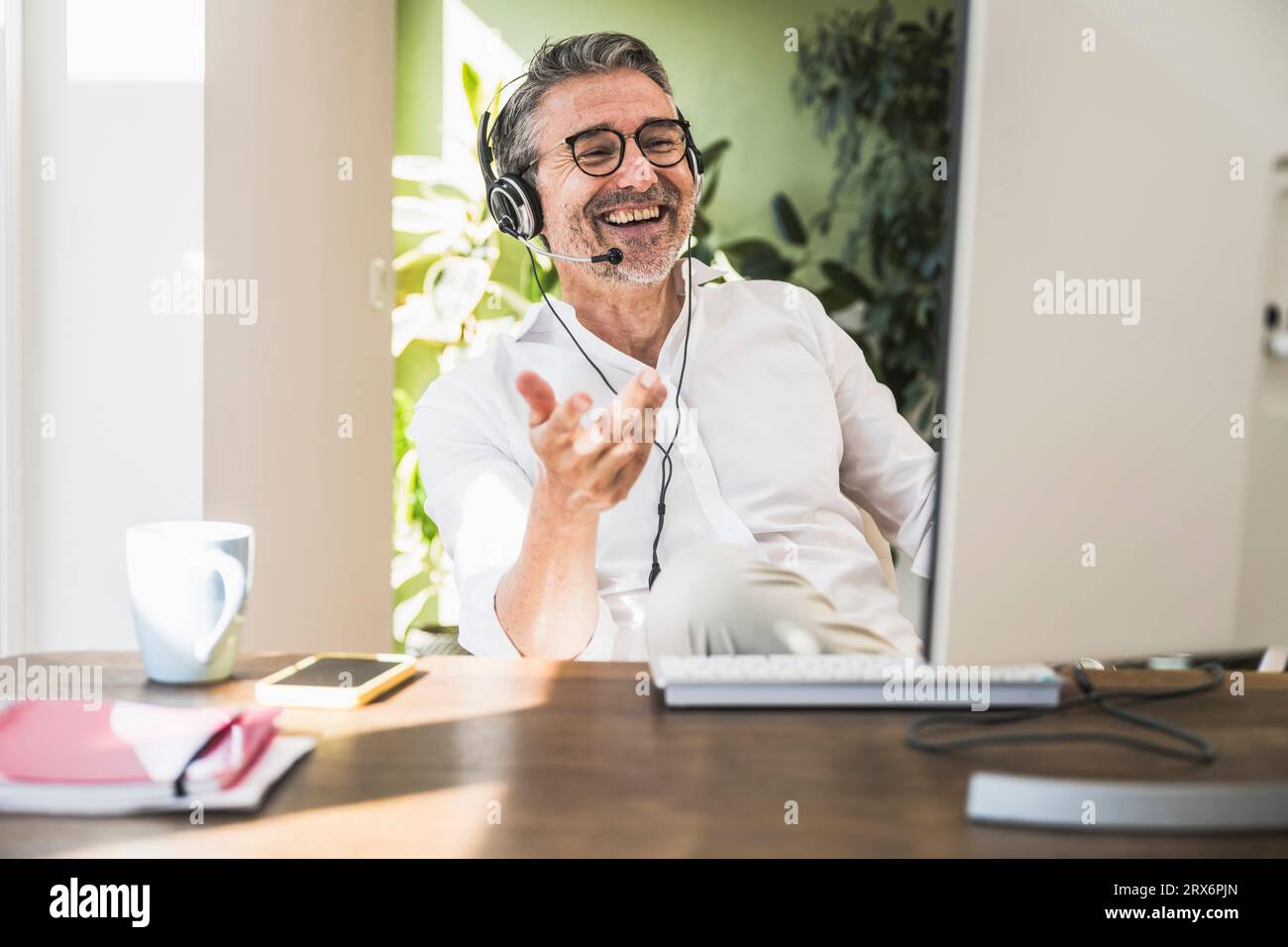 Un rappresentante dell'assistenza clienti felice che parla con la cuffia da casa Foto Stock