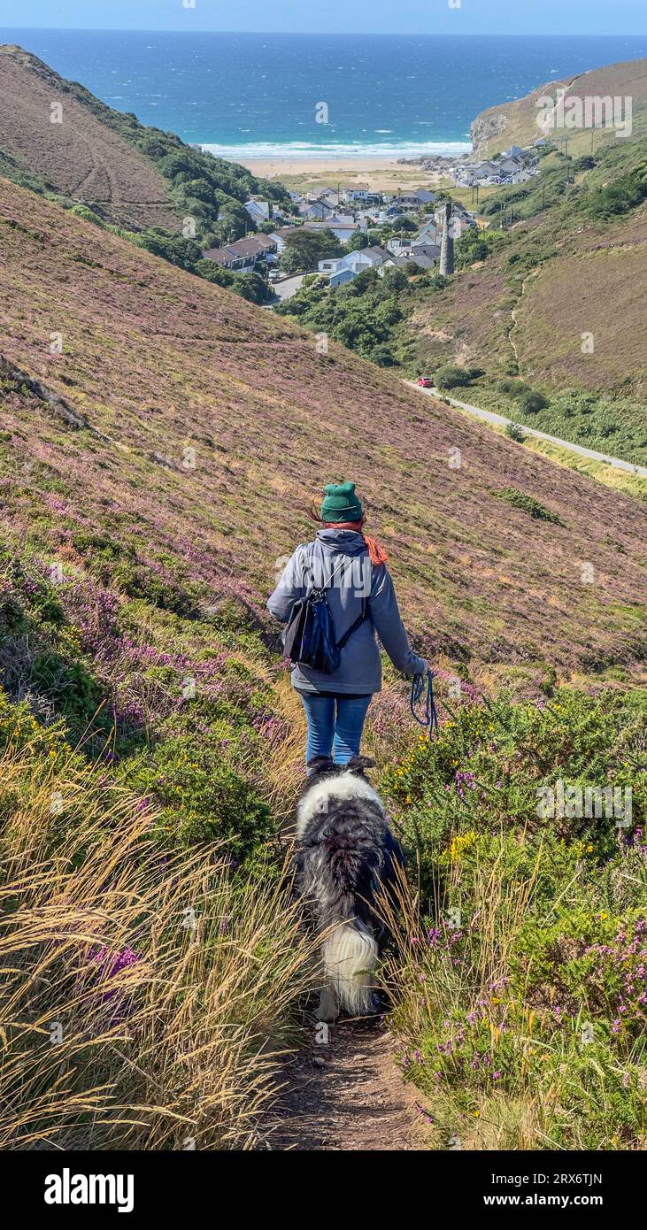 donna con cane collie di confine che si allontana dalla macchina fotografica verso porthtowan, cornovaglia, regno unito Foto Stock