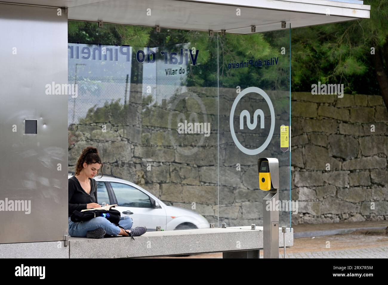 Attraente giovane donna seduta in attesa del treno alla stazione locale della metropolitana di Porto, Portogallo Foto Stock