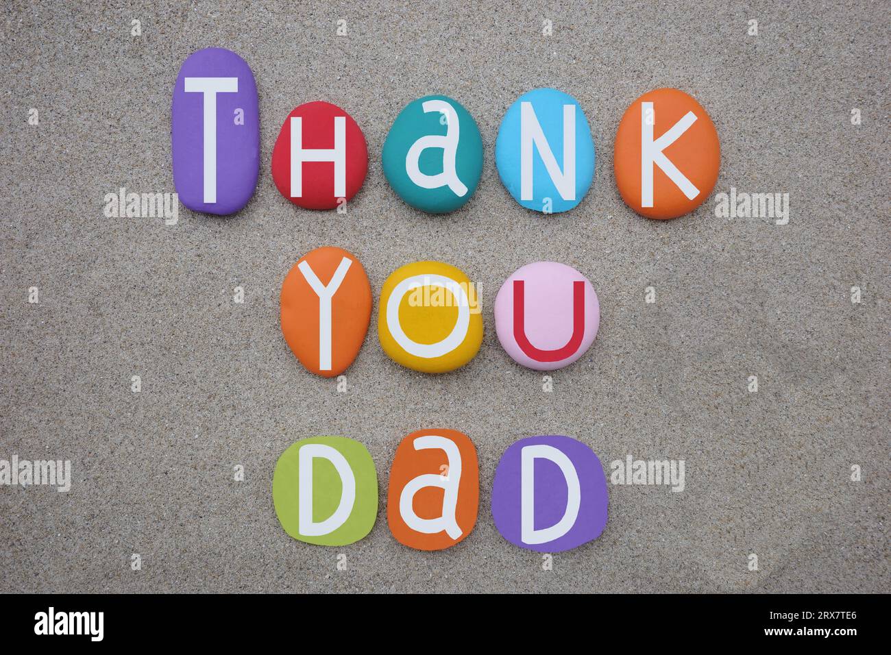Grazie papà, messaggio creativo composto da lettere di pietra multicolore dipinte a mano sulla sabbia della spiaggia Foto Stock
