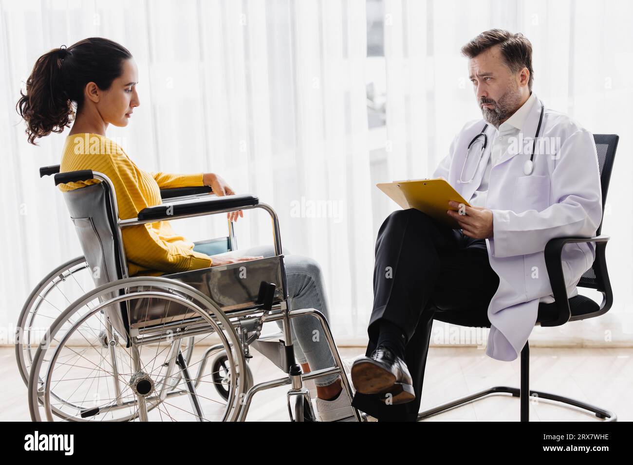 Psichiatra medico raccogliere i dati parlare con il paziente su sedia a rotelle per problemi di salute mentale controllare follow-up in clinica ospedaliera Foto Stock