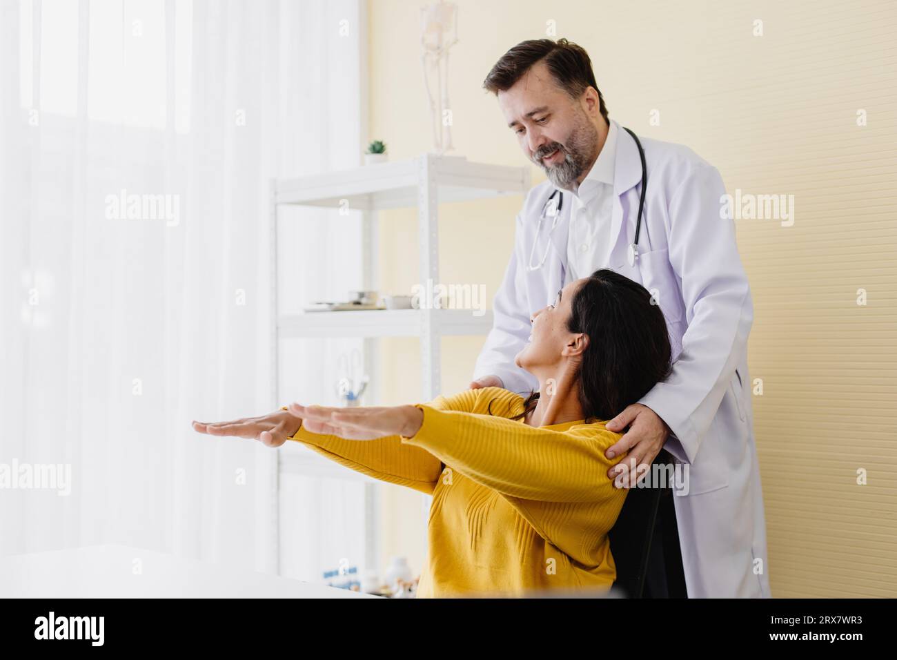 Paziente donna dolore muscolare braccio incontra un medico anziano per la terapia fisica guarigione e recupero schiena lavorare bene e lei molto felice Foto Stock