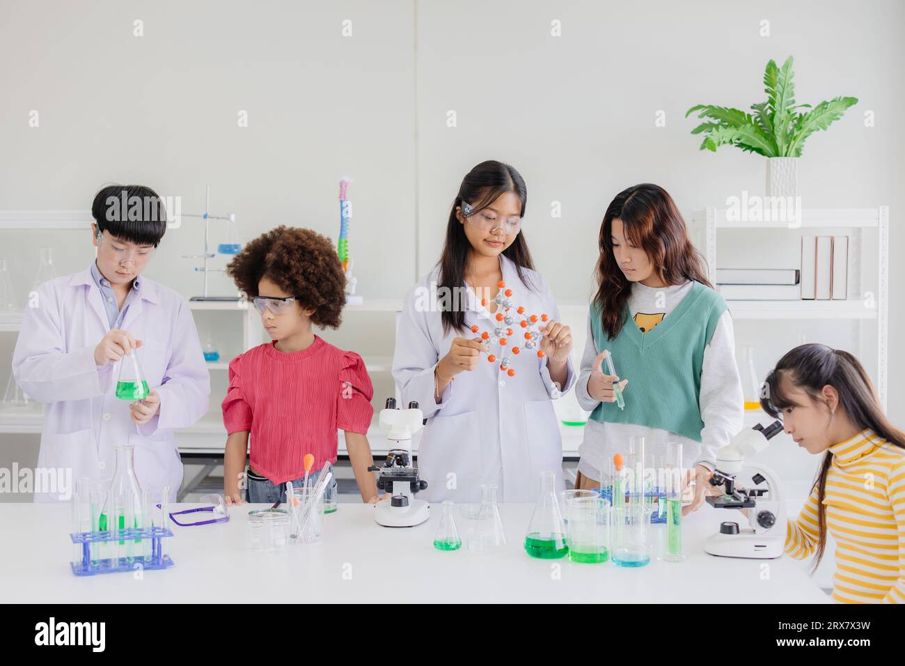 Gruppo di bambini ragazzi adolescenti che giocano in un laboratorio chimico scientifico per l'educazione scolastica Foto Stock