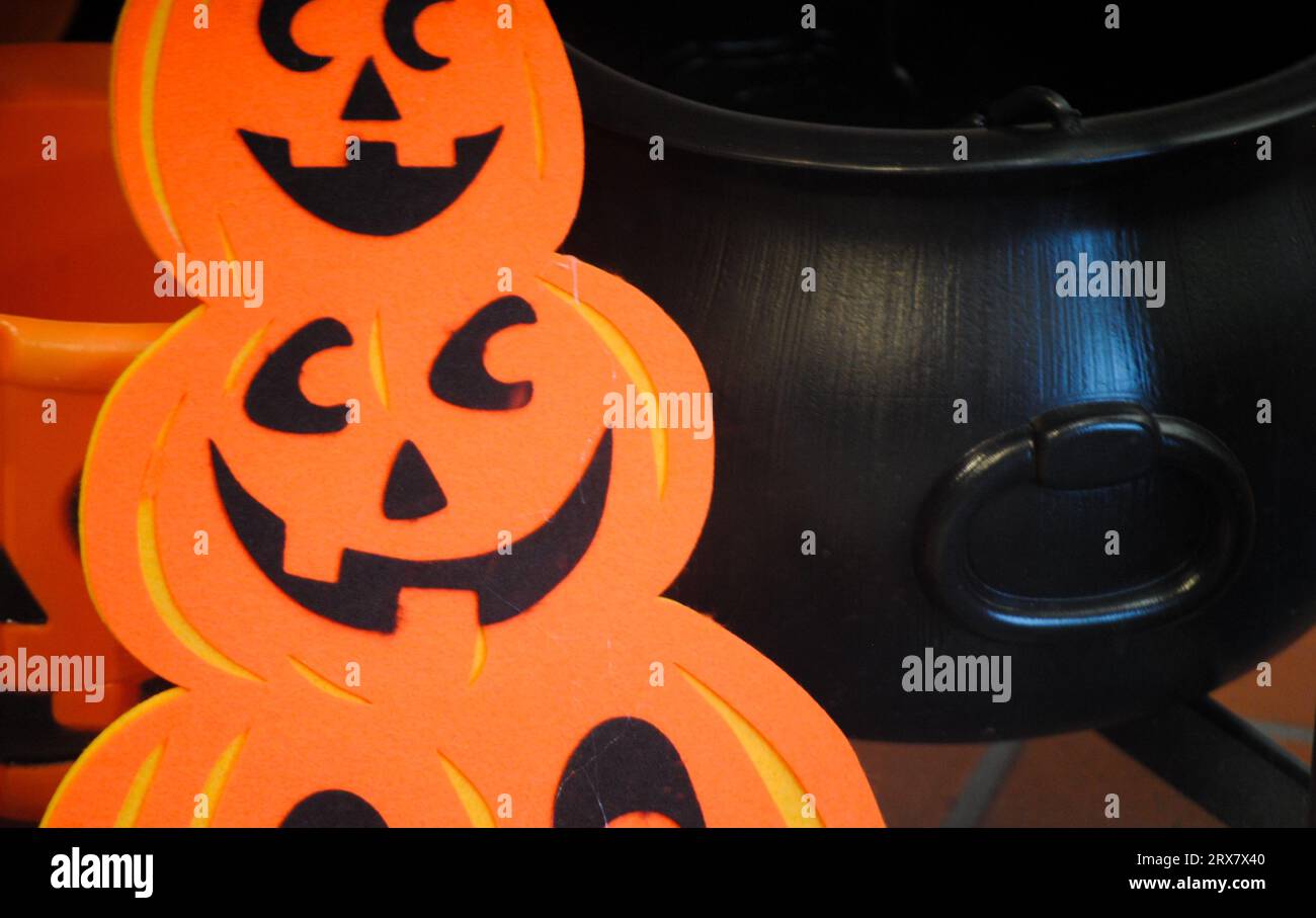 Zucche con sorriso e calderone nero dietro di sé come simboli di Halloween Foto Stock