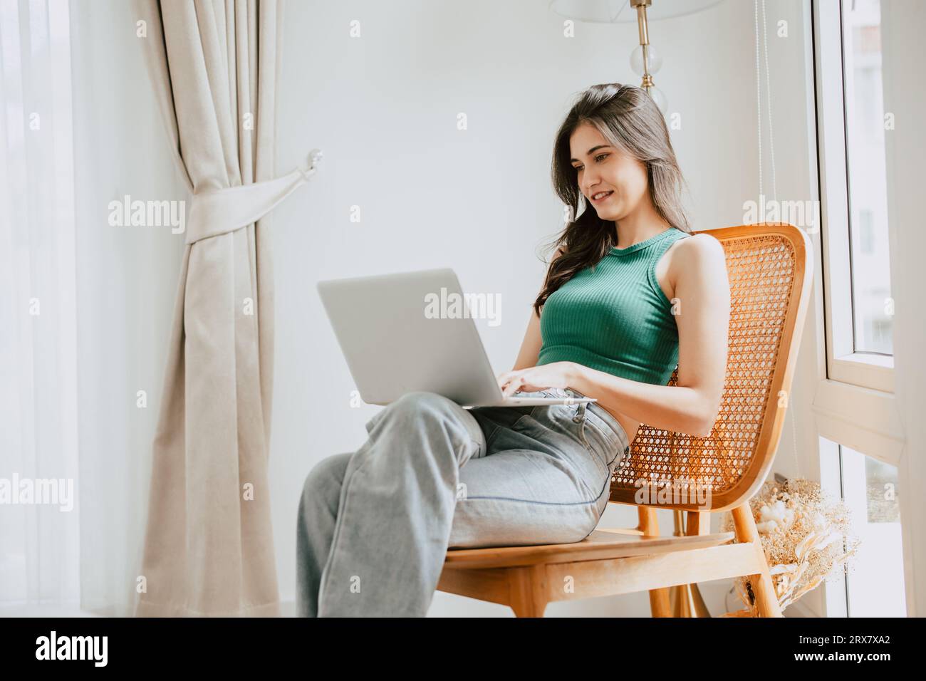 giovane donna felice sorridente digitando al computer portatile rilassarsi al coperto nel salotto di casa. persone che amano il tempo libero con dispositivi tecnologici moderni Foto Stock