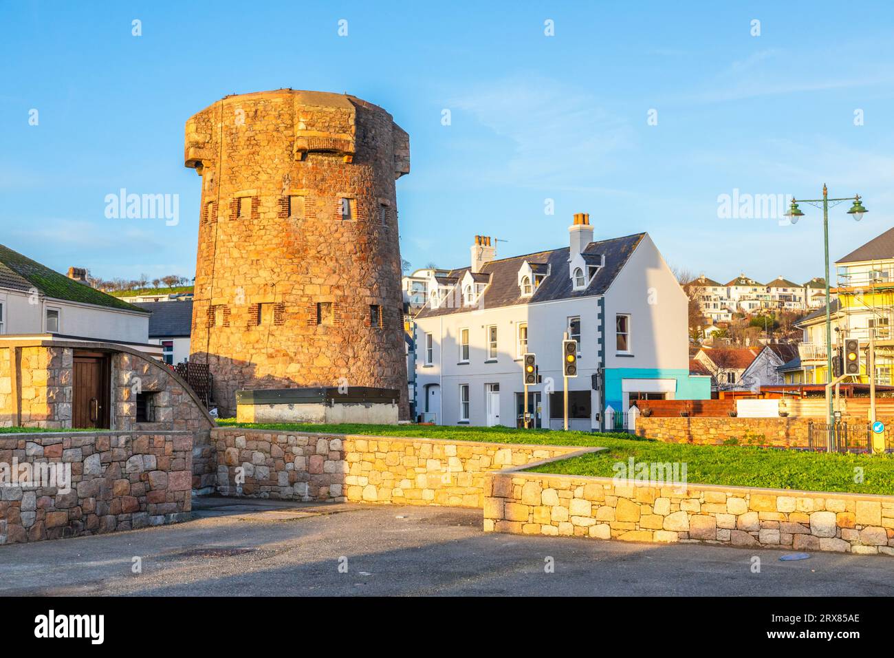 Prima torre di linea di difesa costiera rotonda con quartiere residenziale sullo sfondo, bailiwick of Jersey, Channel Islands, Gran Bretagna Foto Stock