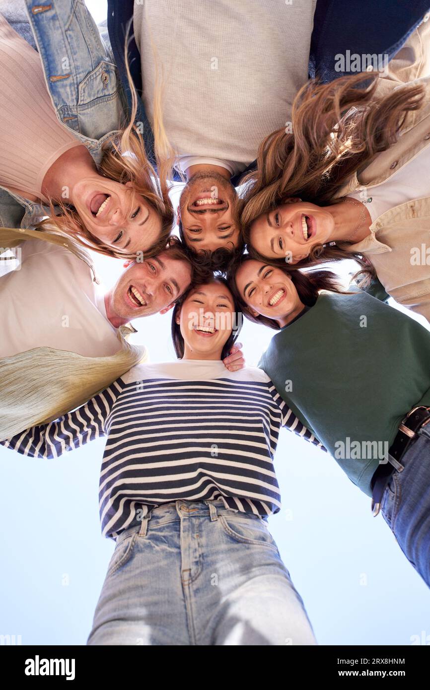 Gruppo verticale multirazziale giovani persone felici in cerchio e sorridenti eccitati alla telecamera. Foto Stock
