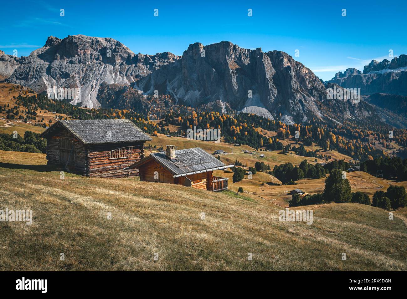 Graziose casette di legno sul pascolo di montagna e splendida cresta di montagna sullo sfondo, gruppo di Puez-Odle, Dolomiti, Italia, Europa Foto Stock