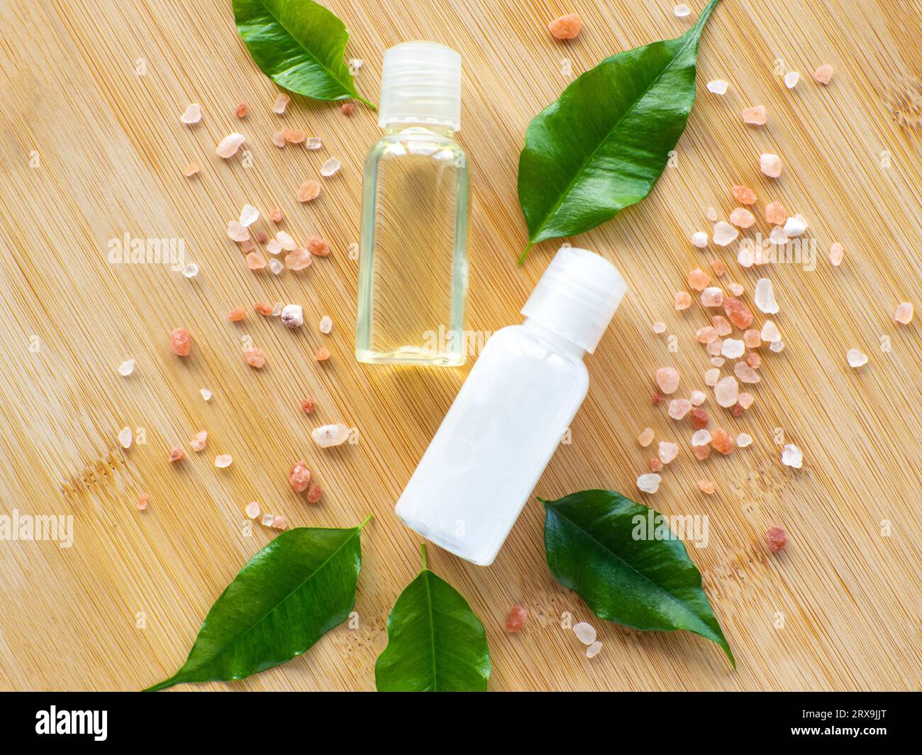 Composizione con foglie verdi, bottiglie di prodotti di bellezza e sale marino su fondo di legno. Carta benessere. Concetto di corpo e cura della pelle con spazio di copia. HY Foto Stock