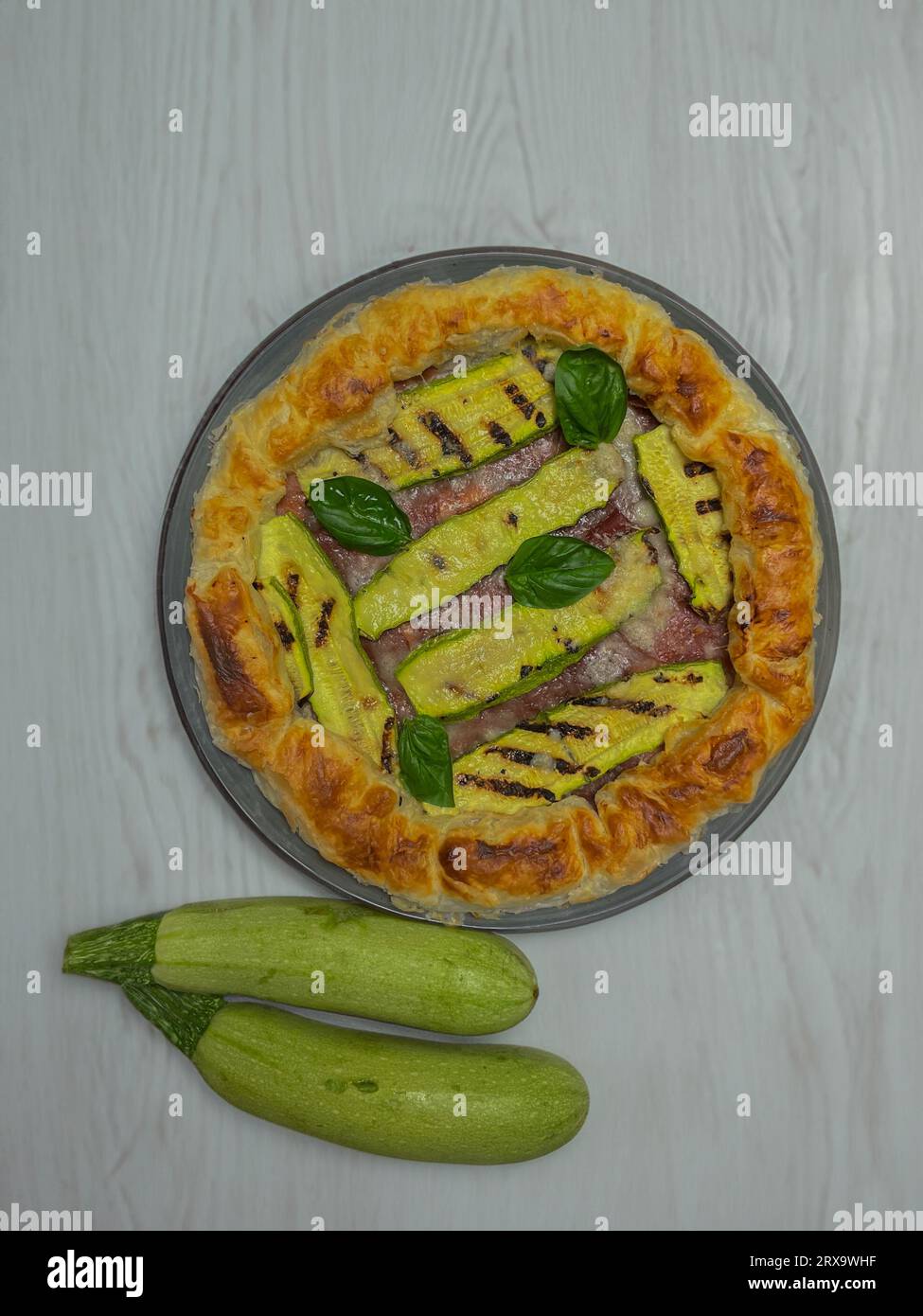 torta salata con zucchine e basilico su un piatto rotondo Foto Stock